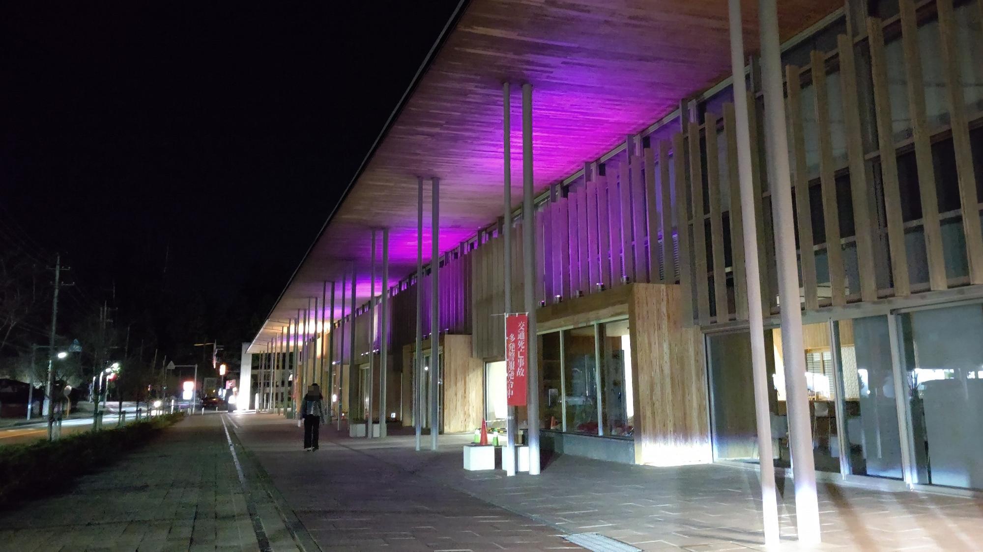 横に長く広がった建物の日光市役所本庁舎が、紫色にライトアップされている写真